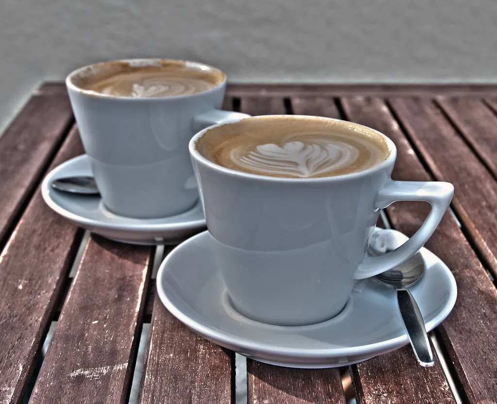 Dos cafés con leche sobre una mesa de madera