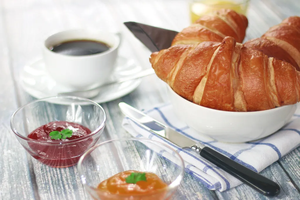 Desayuno con cruasanes, café y mermeladas caseras