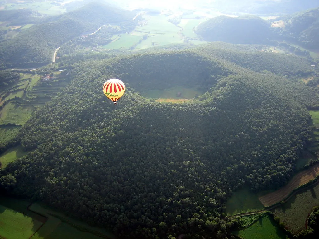 Globo aerostático sobrevolando el cráter boscoso de un volcán