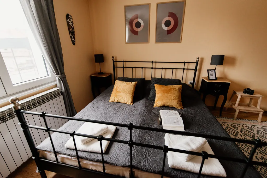Habitación doble con cama de forja y colcha gris