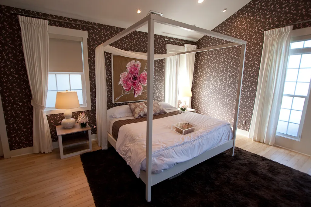 Suite con cama con dosel blanco y grandes ventanas