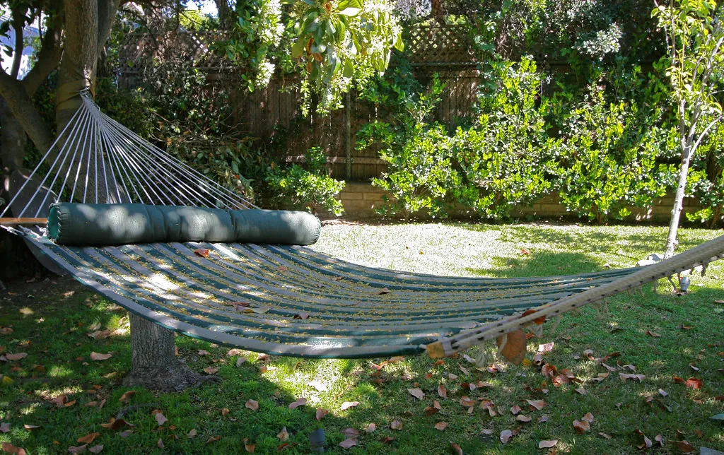 Hamaca colgada en un jardín con sombra de árboles